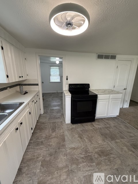A kitchen with white cabinets and a black oven.