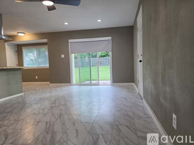 A spacious room with marble flooring and a ceiling fan.
