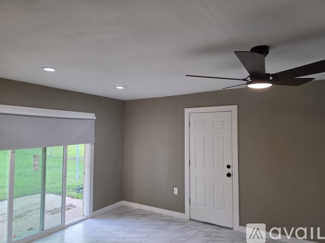 A room with a ceiling fan and sliding glass doors.