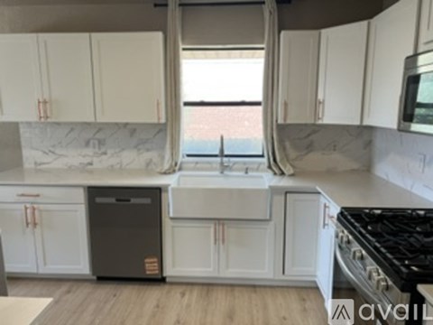 A kitchen with white cabinets and a marble backsplash.