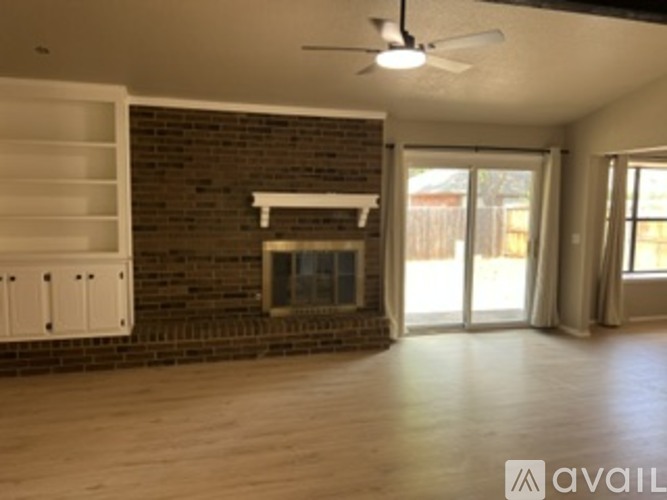 A living room with a brick fireplace and a ceiling fan.