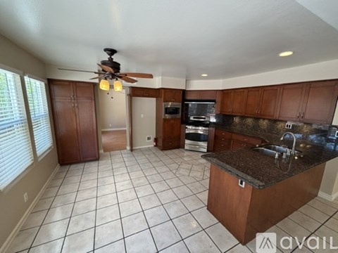 A kitchen with brown cabinets and a black countertop.
