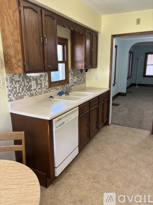 A kitchen with wooden cabinets and a white dishwasher.