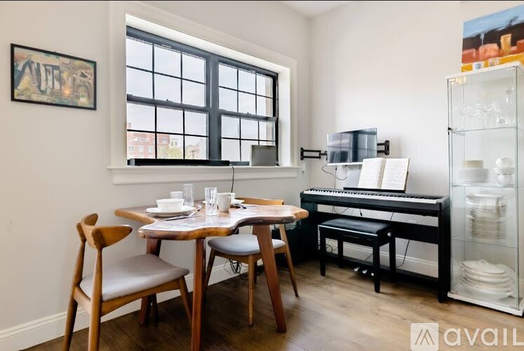 A dining room with a table set for two, a piano, and a chair.