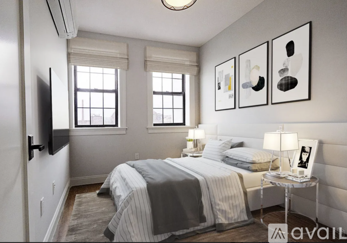 A bedroom with a bed, a nightstand with a lamp, and three framed pictures on the wall.