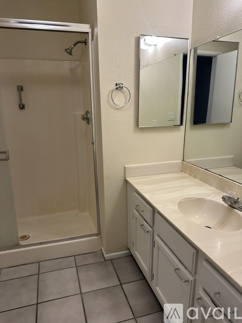 A bathroom with a sink, mirror, and shower.