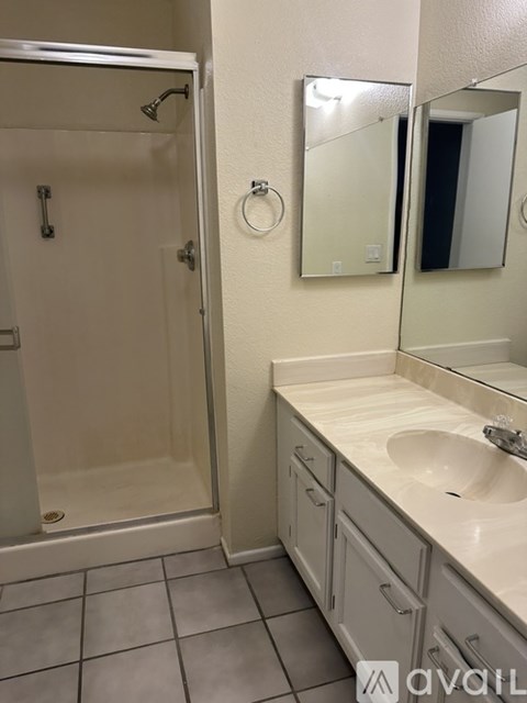A bathroom with a sink, mirror, and shower.
