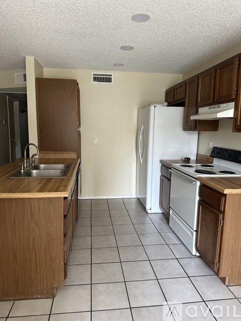 A kitchen with a white refrigerator and wooden cabinets.
