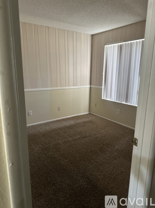 A room with a carpeted floor and a window with blinds.