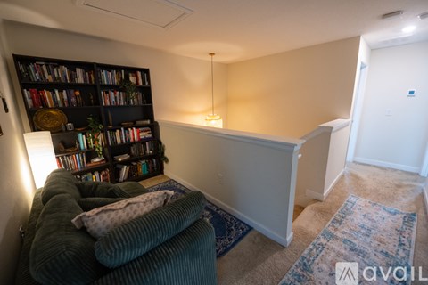 A living room with a green couch and a bookshelf filled with books.