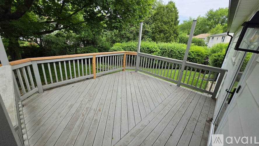 A wooden deck with a railing and a gate leading to a lush green area.
