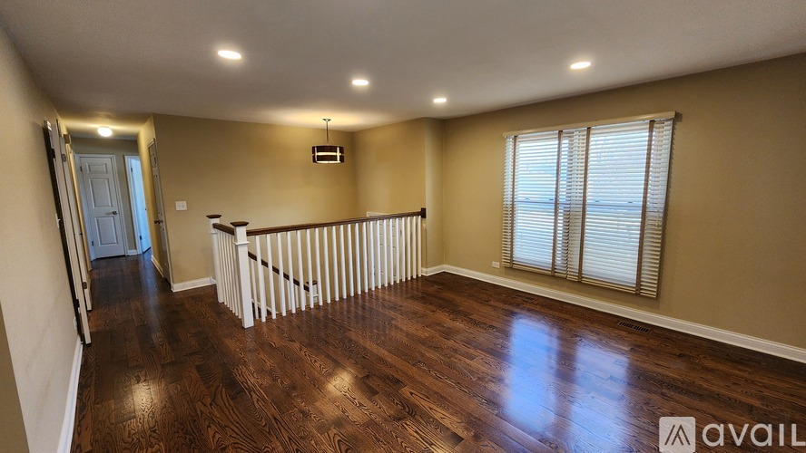 A spacious room with wooden flooring and a white railing.