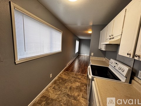 A kitchen with a stove top oven and a window with blinds.