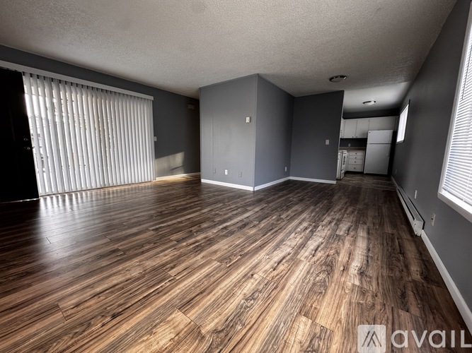 A room with wooden flooring and a window with blinds.