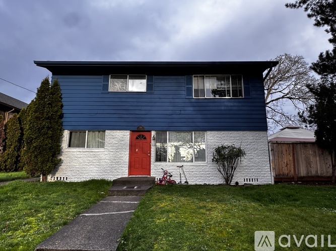 A blue house with a red door and a red bike in front.