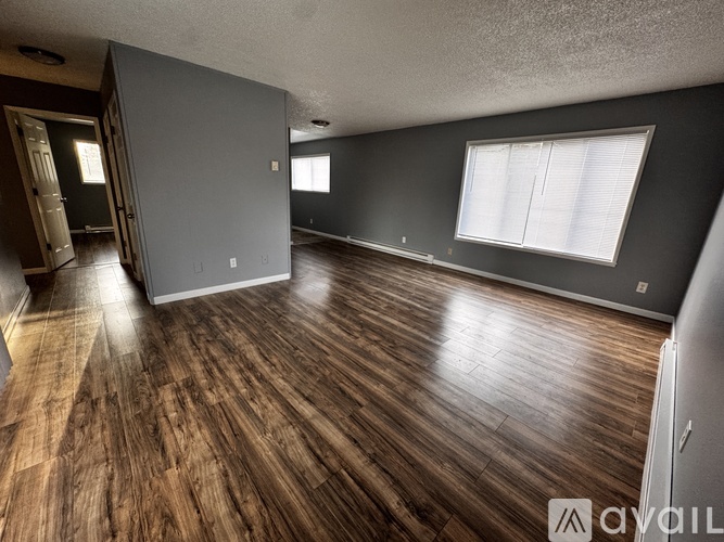 A spacious room with wooden flooring and a large window.