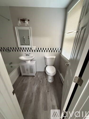 A bathroom with a toilet, sink, and mirror.