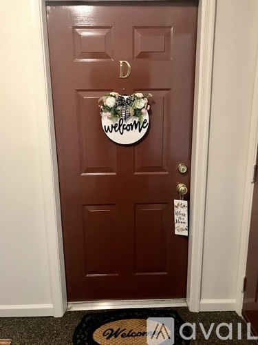 A brown door with a decorative welcome sign on it.