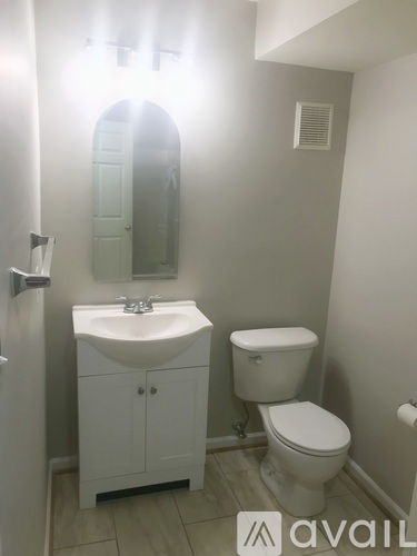 A bathroom with a toilet, sink, and mirror.