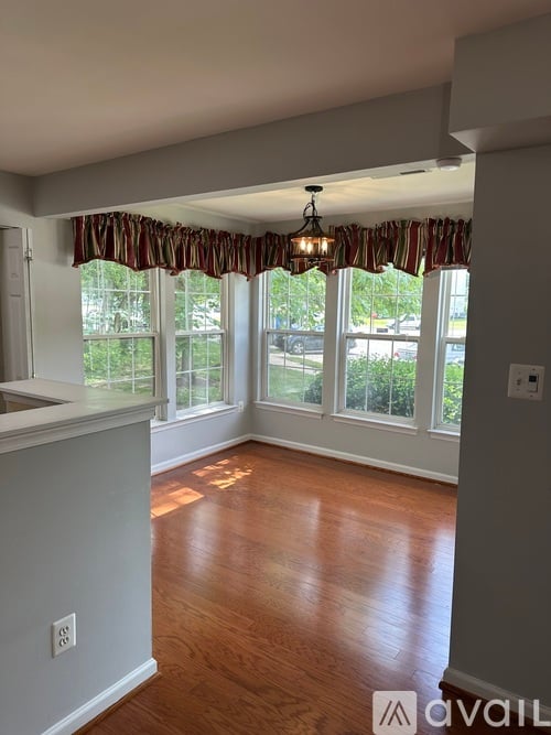 A room with wooden floors and a window with curtains.