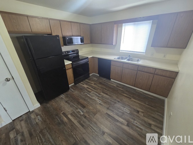 A kitchen with a black fridge, stove, and microwave.