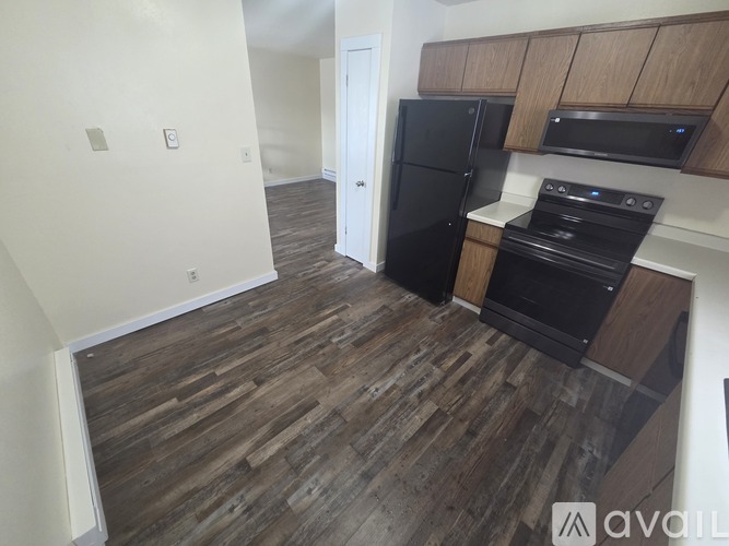 A kitchen with a black fridge and stove top oven.