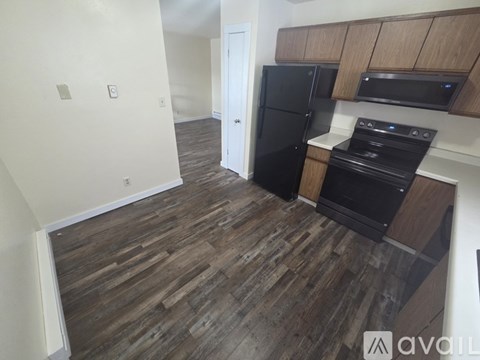 A kitchen with a black fridge and stove top oven.