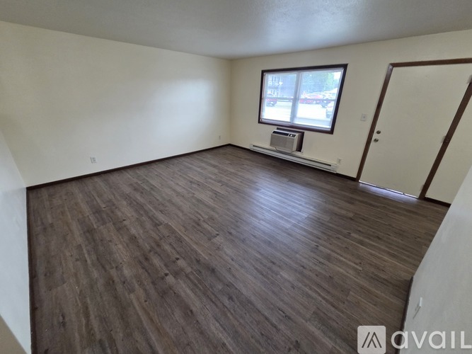 A room with wooden flooring and a window with blinds.