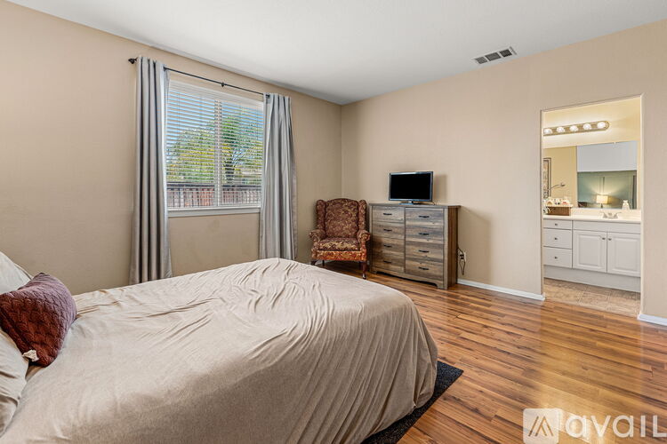 A bedroom with a large bed and a chair by the window.