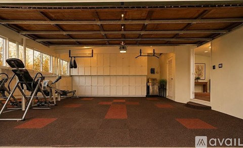 A gym with a brown carpet and a white wall.