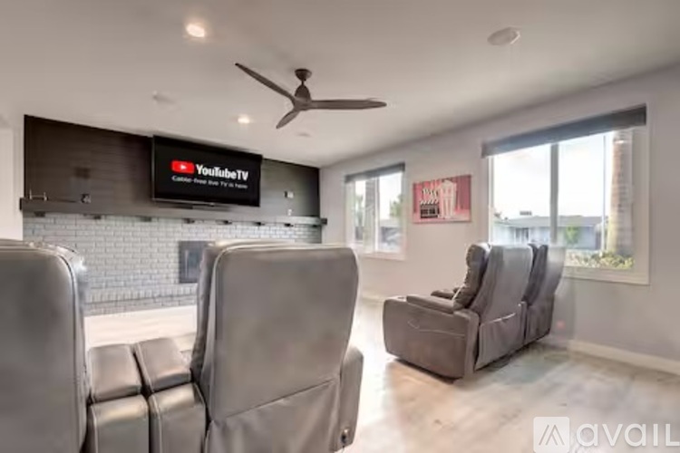 A living room with a flat screen TV mounted above a fireplace and a ceiling fan.