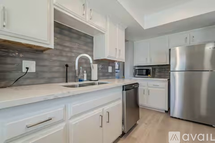 A kitchen with white cabinets and a stainless steel refrigerator.