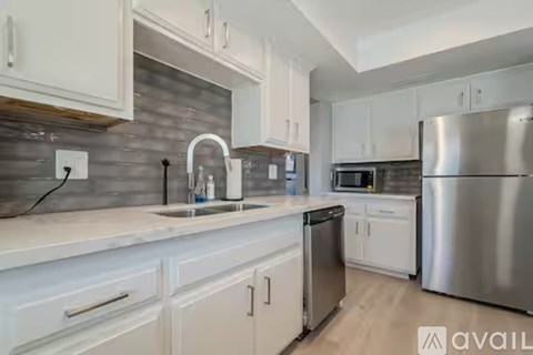 A kitchen with white cabinets and a stainless steel refrigerator.