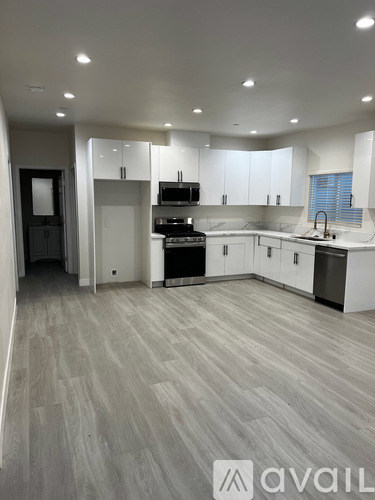 A modern kitchen with white cabinets and a grey floor.