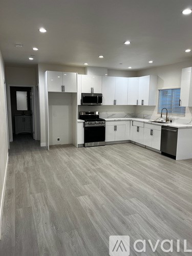 A modern kitchen with white cabinets and a grey floor.
