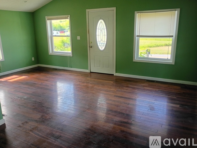 A room with a wooden floor and a white door with a glass window on the right side.