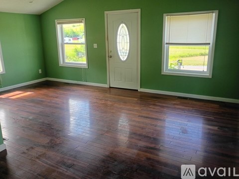 A room with a wooden floor and a white door with a glass window on the right side.