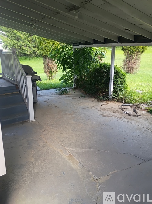 A concrete porch with a white railing and a green lawn in the background.