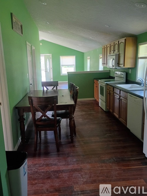A kitchen with green walls and wooden floors.