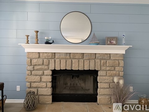 A stone fireplace with a mirror above it and some decorations on top.