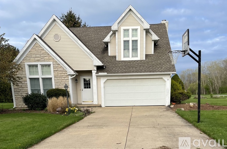 A house with a garage and a basketball hoop in the front yard.