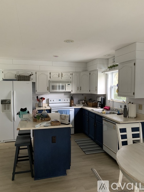 A kitchen with white cabinets and a white fridge.