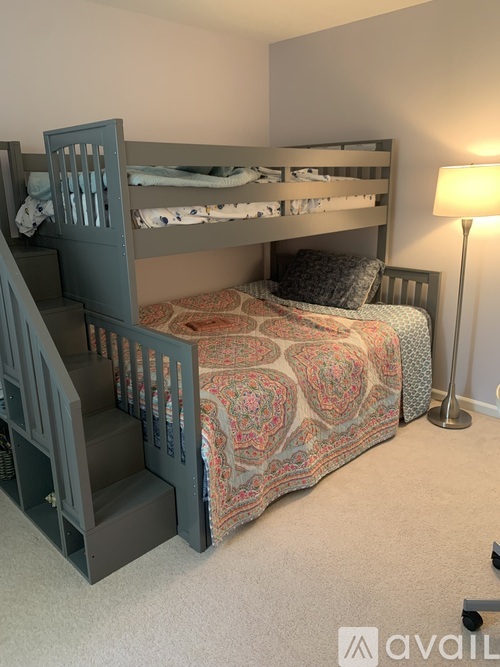 A bedroom with a bunk bed and a bed with a patterned bedspread.