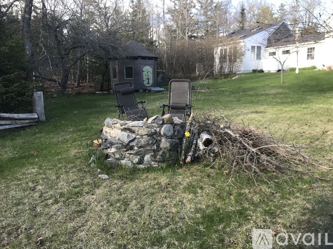 A black chair is leaning against a stone wall in a yard.