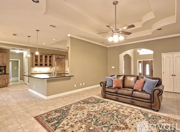 A living room with a brown leather couch and a rug in the middle.