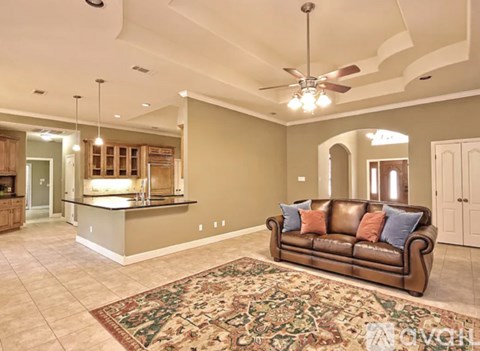 A living room with a brown leather couch and a rug in the middle.