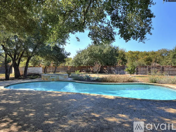 A pool surrounded by trees and bushes with a stone wall in the background.