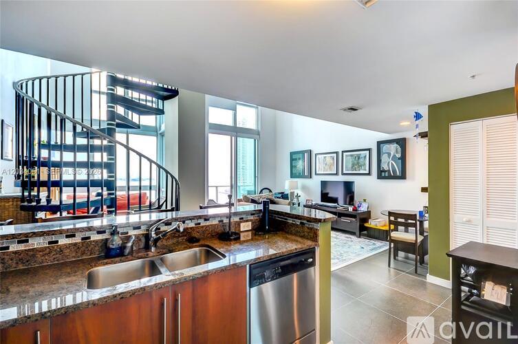 A modern kitchen with a spiral staircase in the background.