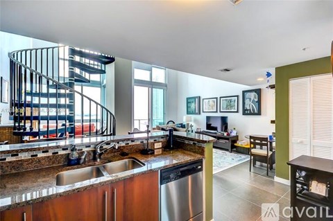 A modern kitchen with a spiral staircase in the background.