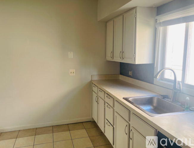 A kitchen with white cabinets and a tiled floor.
